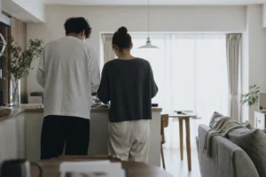 明るいリビングで並んで家事をする男女の後ろ姿。本編の前の日常描写が長いことを表したイメージ